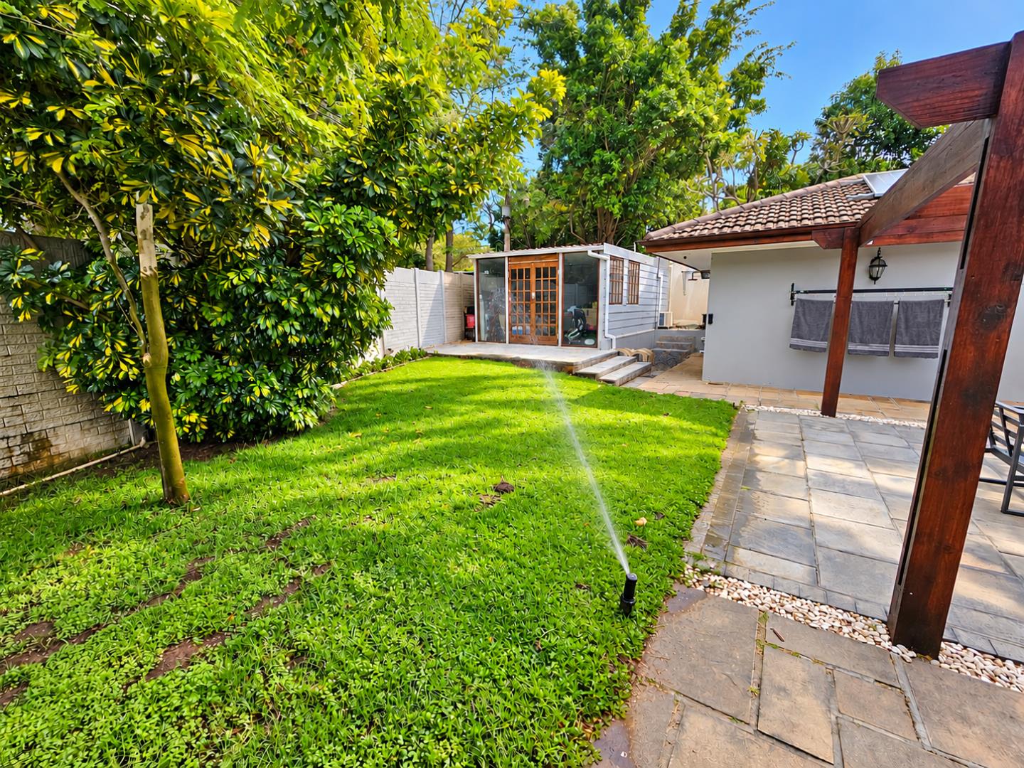 769572_Sunlit_Backyard_Garden_with_Sprinkler.png